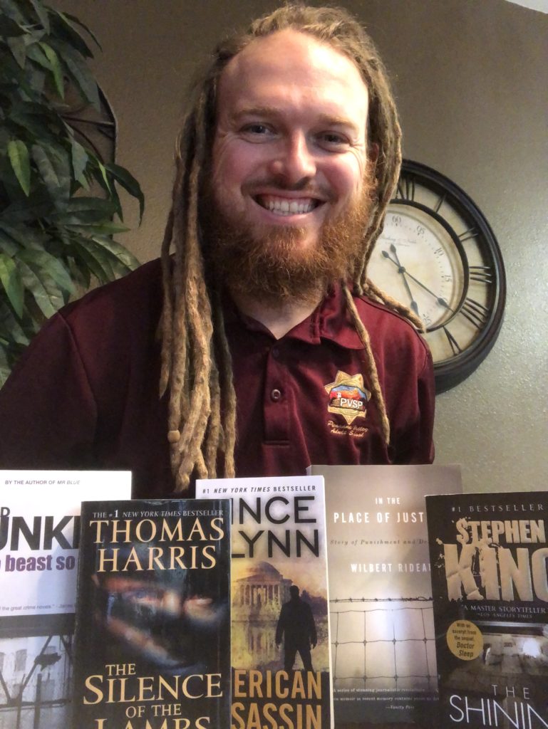 Photo of Beau, a friend of the MJ PROJECT with a display of donated books